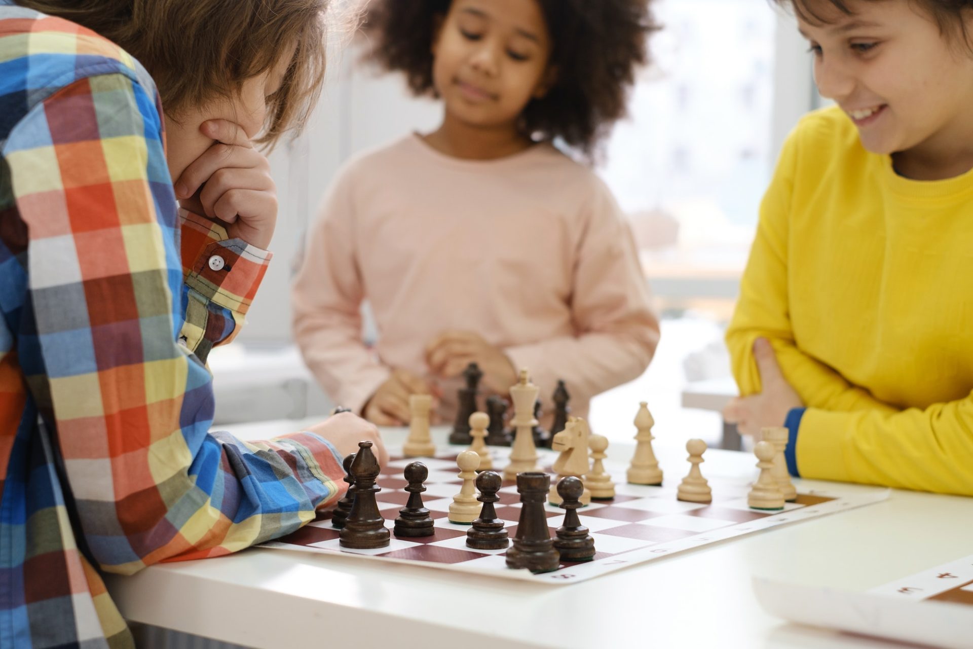 multiethnic-kids-playing-chess-board-game-at-school-e1650351500800.jpg